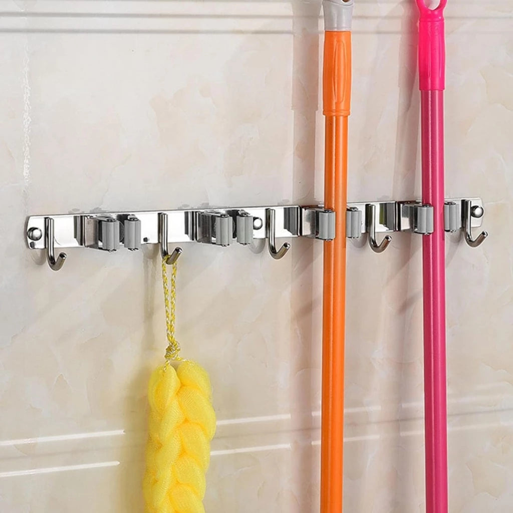 Várias vassouras e rodos pesados pendurados no suporte, demonstrando a estabilidade da fixação.