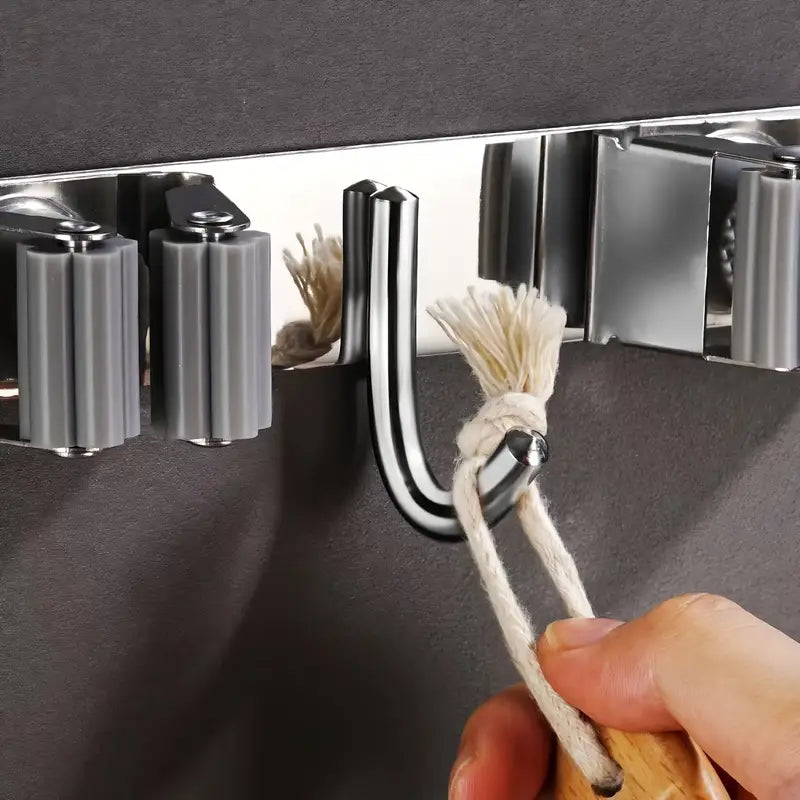 Visão dos ganchos fixos entre as garras, ideais para pendurar panos de limpeza, escovas ou pás.